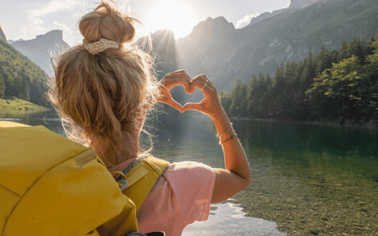 Femme dans un paysage faisant un coeur avec ses mains