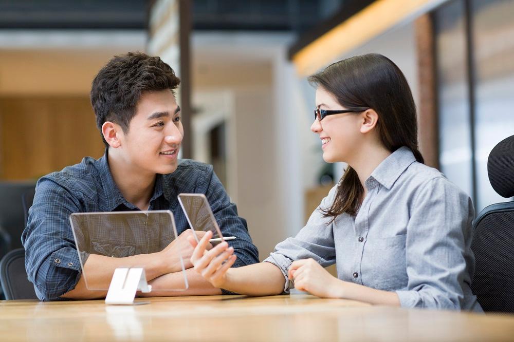 deux personnes asiatiques discutent av ec des tablettes