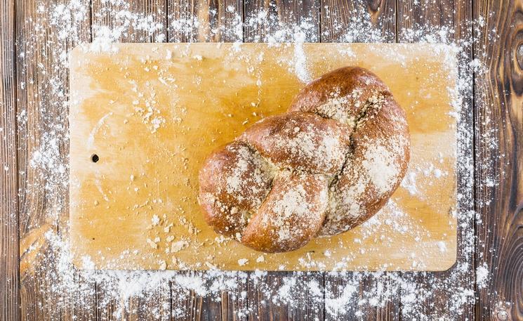 braided-bread-on-chopping-board-with-spread-white-flour