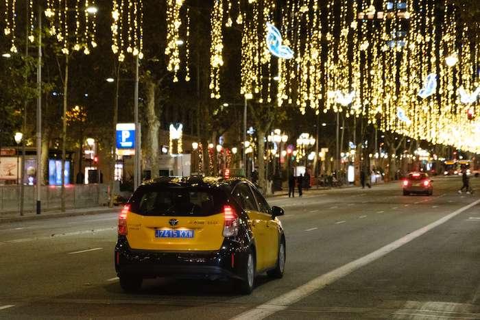un taxi en train de rouler la nuit sur une avenue avec des décorations de Noel à Valencia