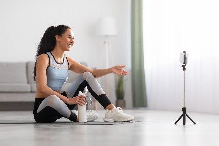 Femme sportive avec une bouteille d'eau qui regarde une caméra téléphone