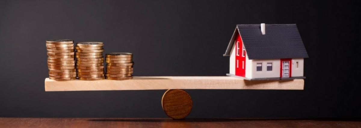 Une balance entre des pièces de monnaie et une maison