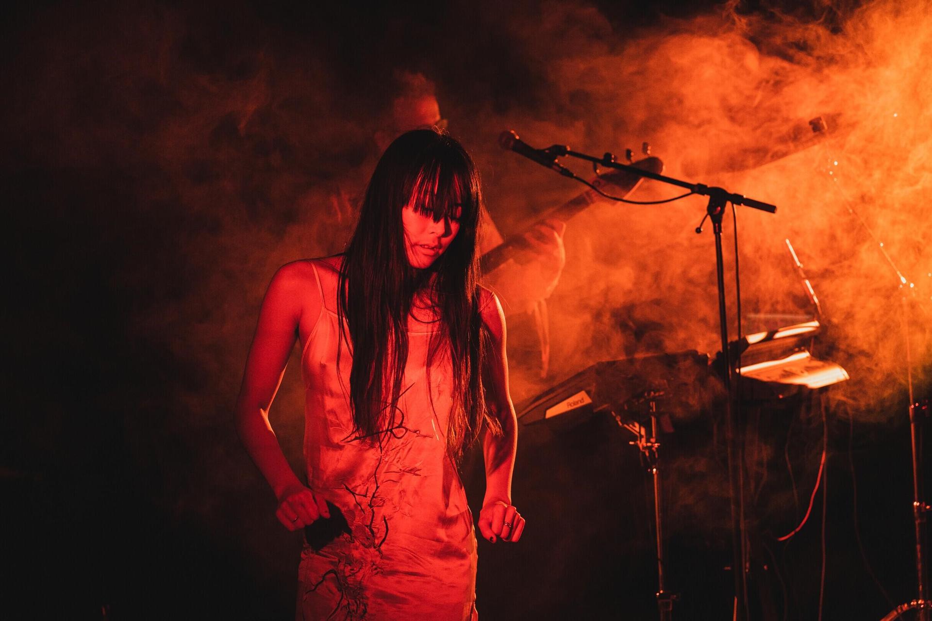 Représentation de Hanako Hayakawa pendant le Gig Theatre Spectacles devant des musiciens et un écran de fumée rouge