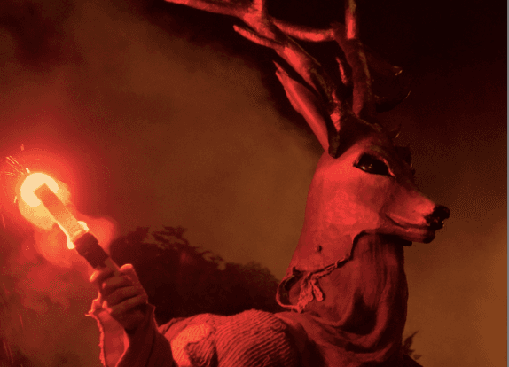 quelqu'un déguisé en cerf avec un flambeau