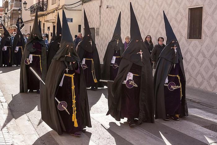 des personnes en costumes noirs traditionnels en train de défiler pour la semana santa à Valencia