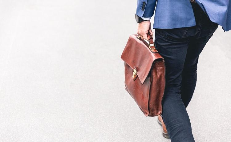 un homme d'affaire en costume bleu marche avec sa sacoche en cuir-marten bjork-unsplash