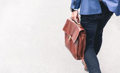 un homme d'affaire en costume bleu marche avec sa sacoche en cuir-marten bjork-unsplash