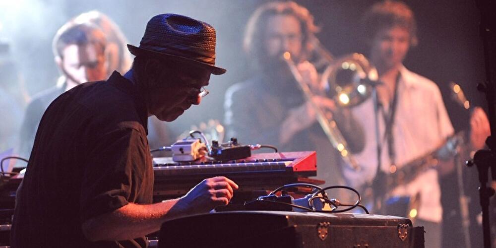 DJ au premier plan devant des platines et une foule qui danse