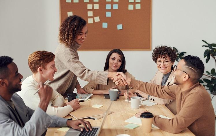 des gens se serrent la main autour d'une table de réunion