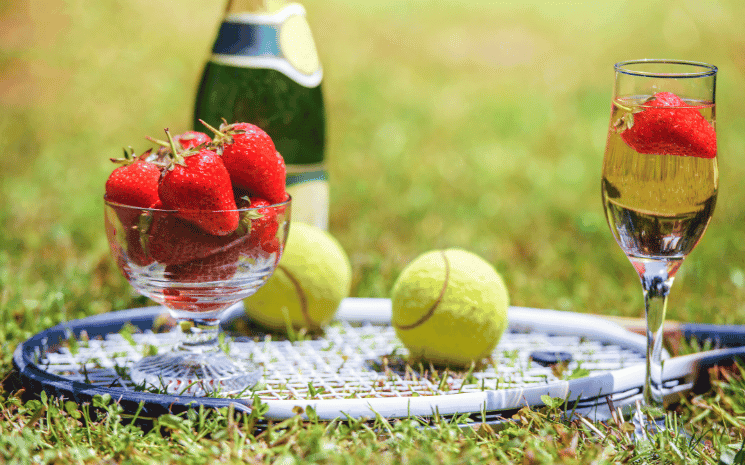 Un gazon à Wimbledon avec une raquette, des balles de tennis et des fraises