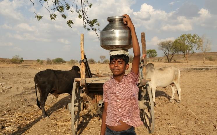 Jeune Indien portant un pot d'eau dans la campagne