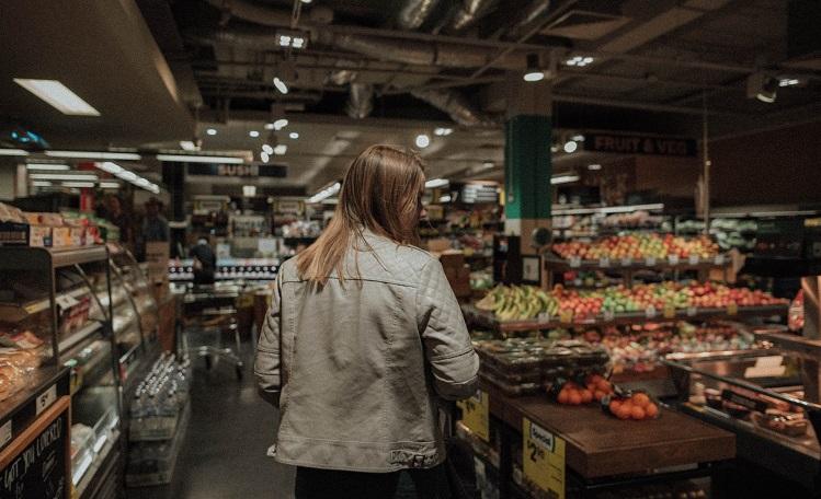 femme debout fait ses courses de fruits et légumes au supermarché