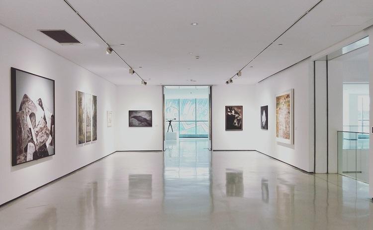 grande salle dans une galerie d'art avec des tableaux accrochés -dannie-jing-unsplash