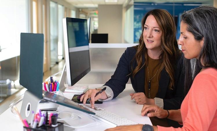 deux femmes travaillent devant un écran d'ordinateur