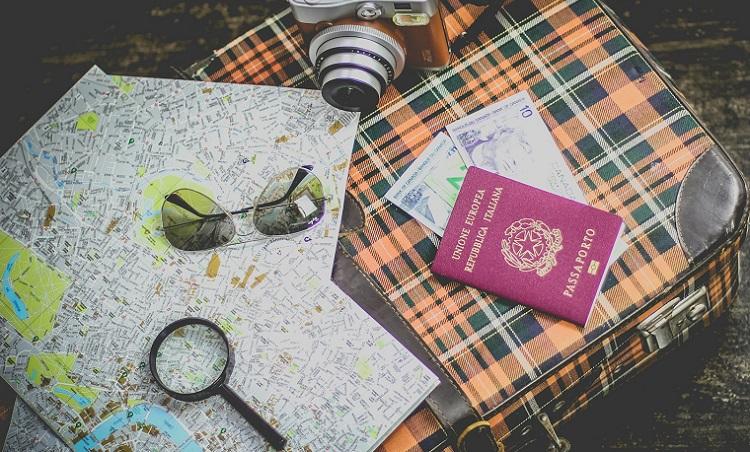 passeport sur une valise avec une carte une loupe et des lunettes de soleil