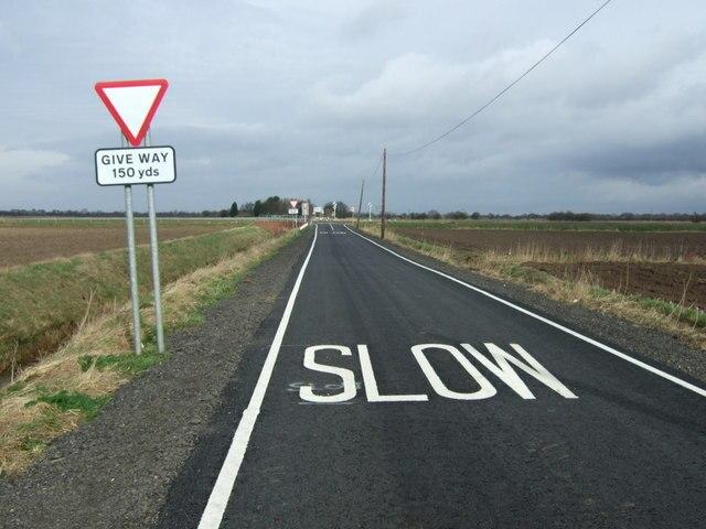 image d'une route sur laquelle est écrit "Slow" à la peinture blanche