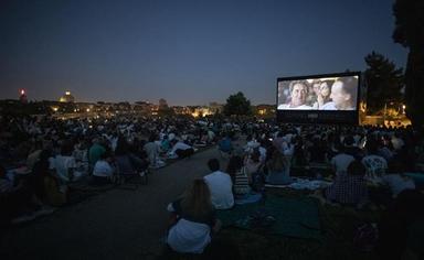 des gens regardent un écran de cinéma en plein air de nuit