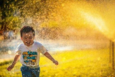 Un enfant sous des jets d'eau.