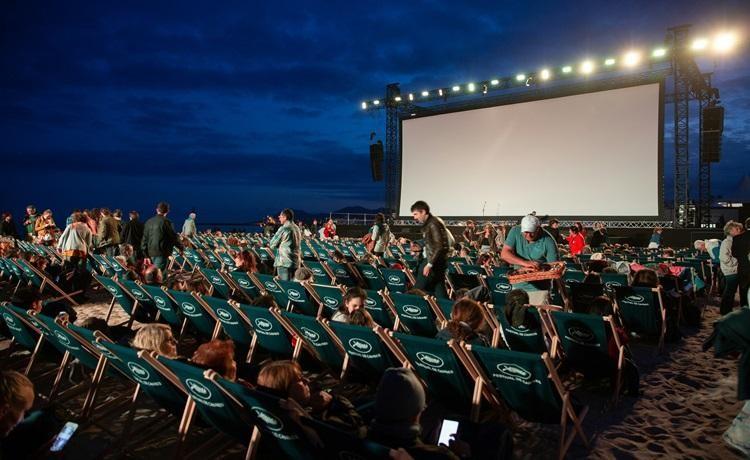 chaises longue devant un grand écran de cinéma en plein air la nuit
