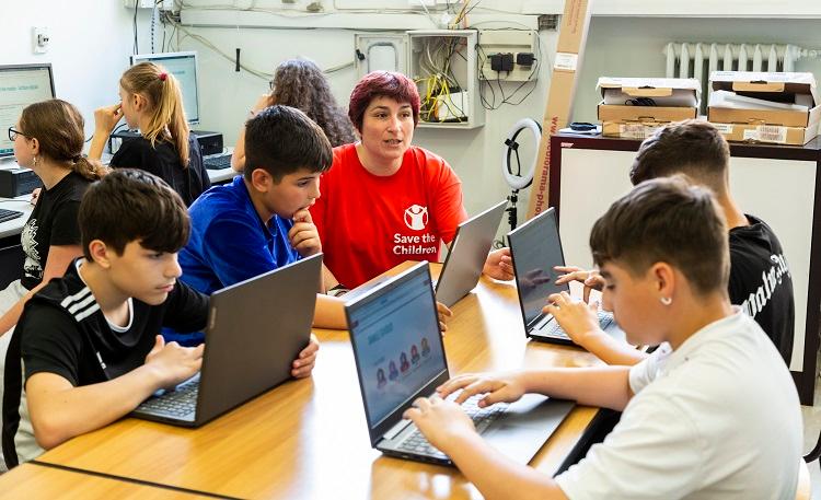 des jeunes apprennent à utiliser un ordinateur portabe en classe