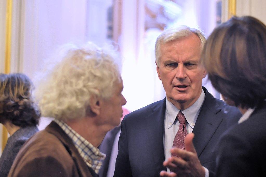 Michel Barnier en train de parler à deux autre personnes de dos.