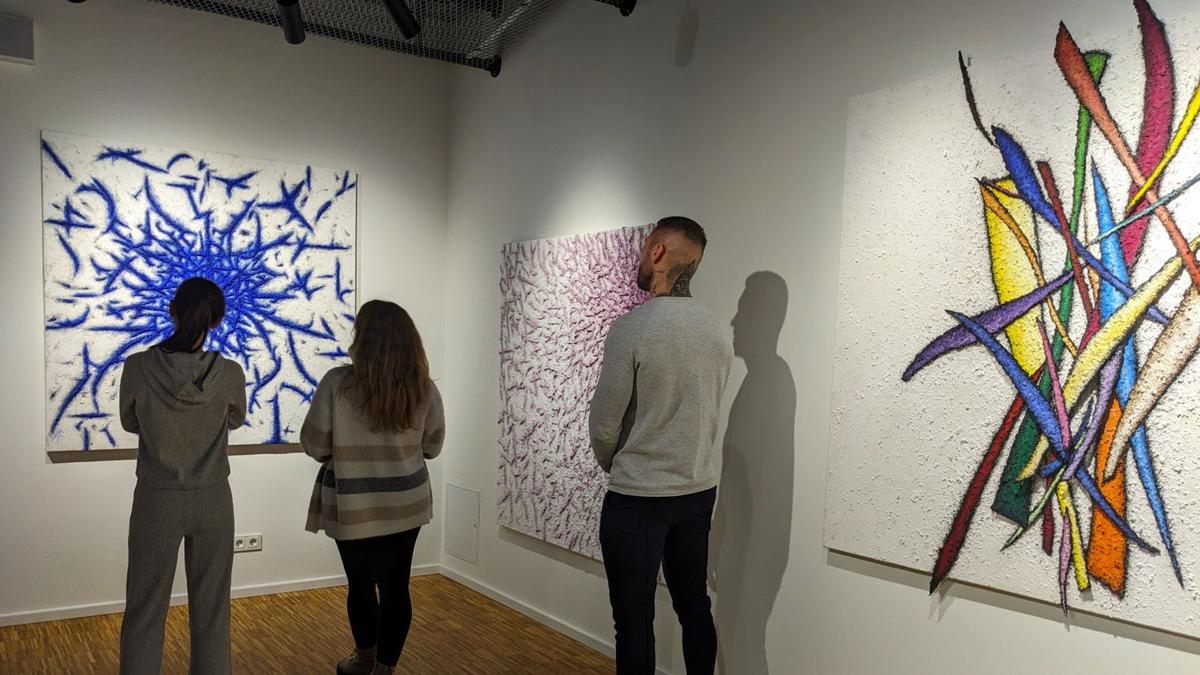 Trois personnes observant un tableau