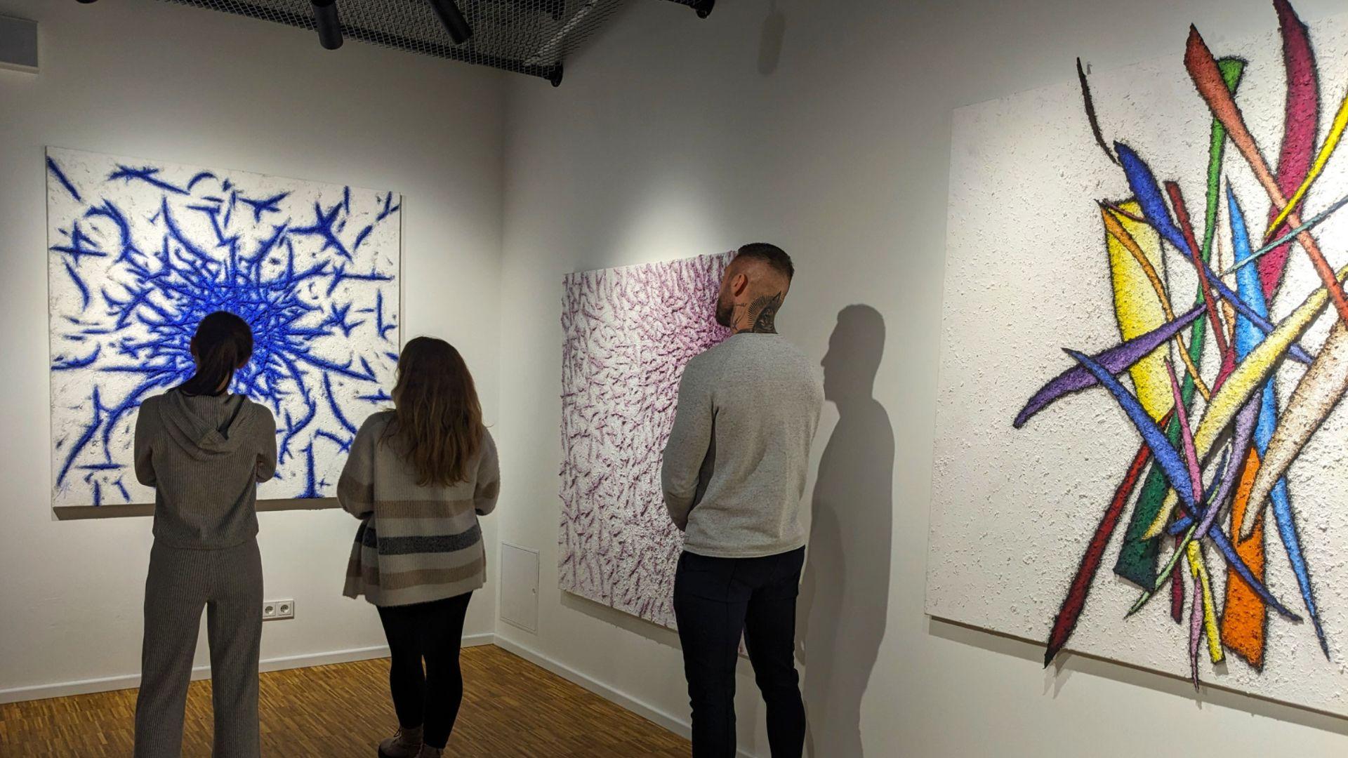 Trois personnes observant un tableau