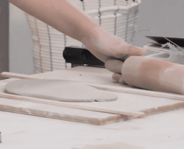 Vue rapprochée d'une main utilisant un rouleau pour travailler l'argile lors d'un atelier de poterie à l'Union Française d'Istanbul.