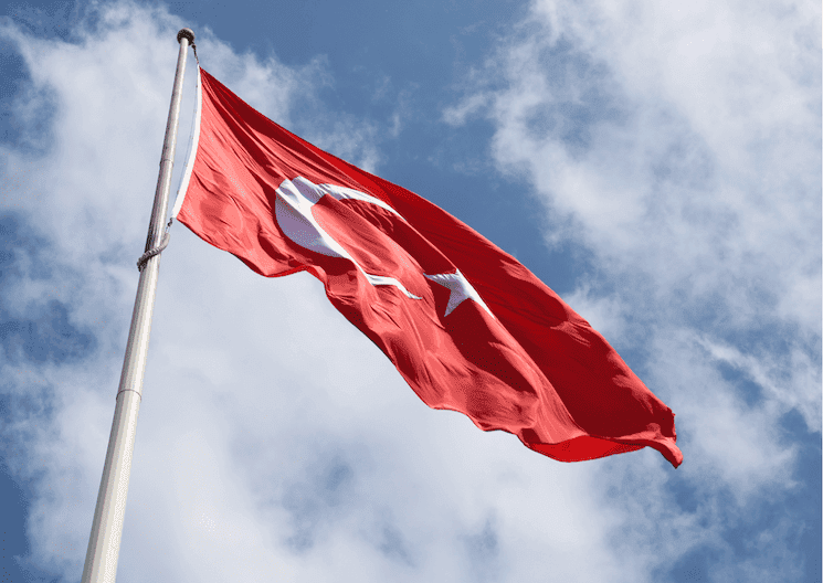 Drapeau turc flottant sous un ciel bleu, symbolisant les changements en Turquie au 1er janvier 2025.