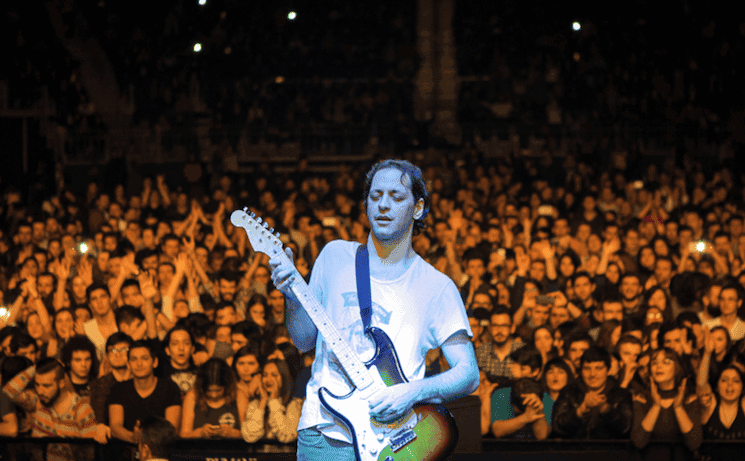 Le guitariste du groupe Duman en pleine performance sur scène, entouré d’un public enthousiaste lors d’un concert de rock légendaire à Izmir en janvier 2025.