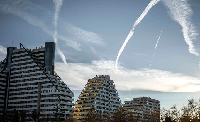 batiments d'un ville espagnole avec ciel bleu et traces blanches d'avions