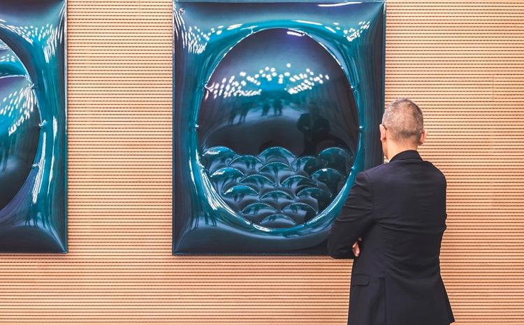 une homme regarde une oeuvre exposée