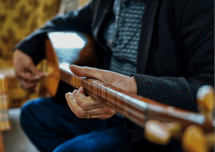 Gros plan sur un musicien jouant du saz, un instrument emblématique de la musique turque.