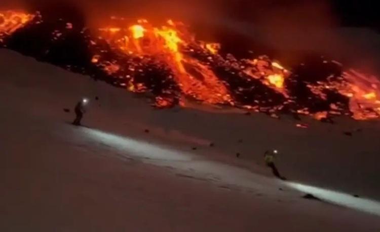 skieurs la nuit sur la neige du volcan etna avec coulée de lave