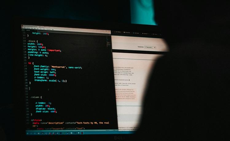 un homme en noir devant un écran noir d'ordinateur