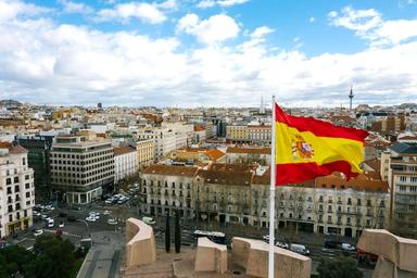 drapeau espagnol rouge et jaune à Madrid un jour nuageux avec vue sur une rue et des immeubles