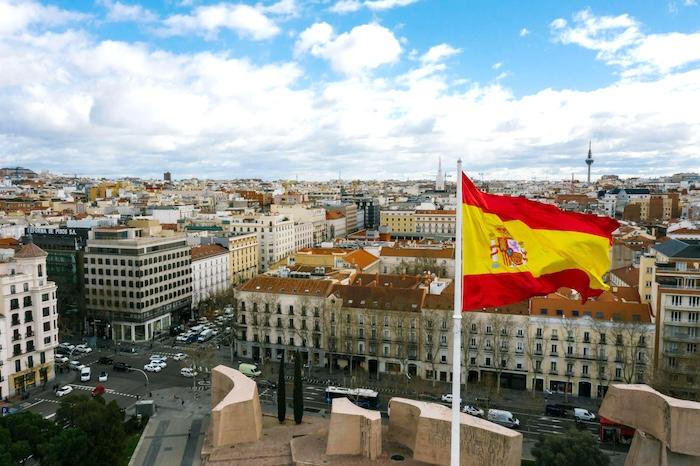 drapeau espagnol rouge et jaune à Madrid un jour nuageux avec vue sur une rue et des immeubles