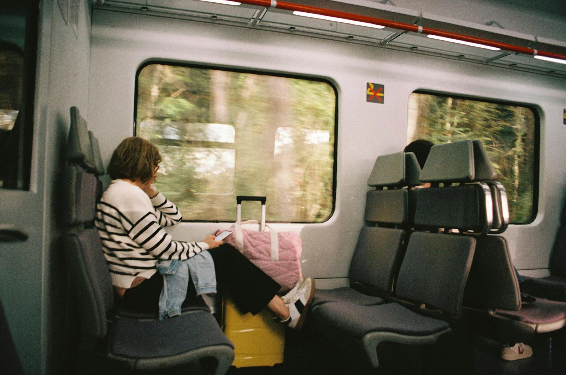 Photo d'une voyageuse lisant sur un siège de train avec des bagages