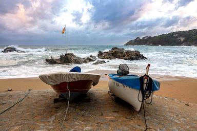 une plage de sable en espagne avec deux bateaux de pecheurs la mer et le ciel nuageux