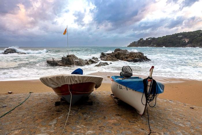 une plage de sable en espagne avec deux bateaux de pecheurs la mer et le ciel nuageux