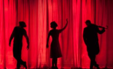 trois personnes devant un rideau de théâtre rouge
