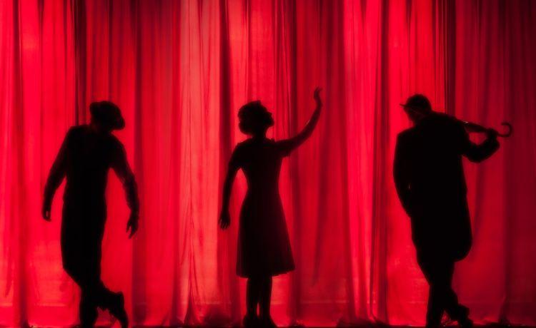 trois personnes devant un rideau de théâtre rouge_0