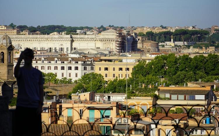 un homme debout devant une vue manoramique de Rome