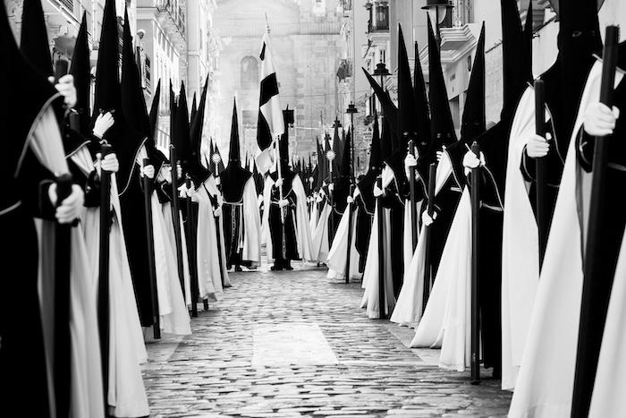 photo en noir et blanc de nazareens avec capirotes lors d'une procession de la semaine sainte en espagne