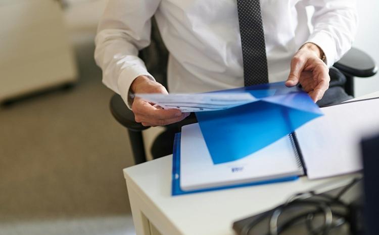 un homme en chemise banche et cravate tenant un dossier