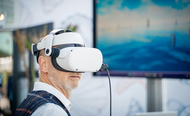 un homme porte un masque de réaité virtuelle devant un ordinateur