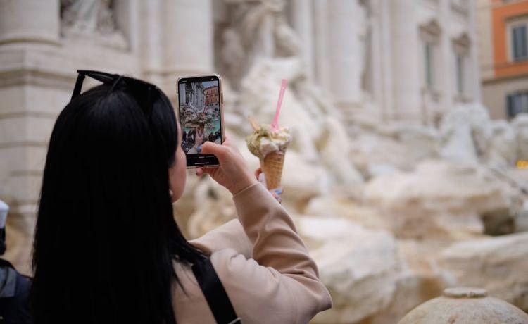 une touriste photographie sa glace devant un monument à rome