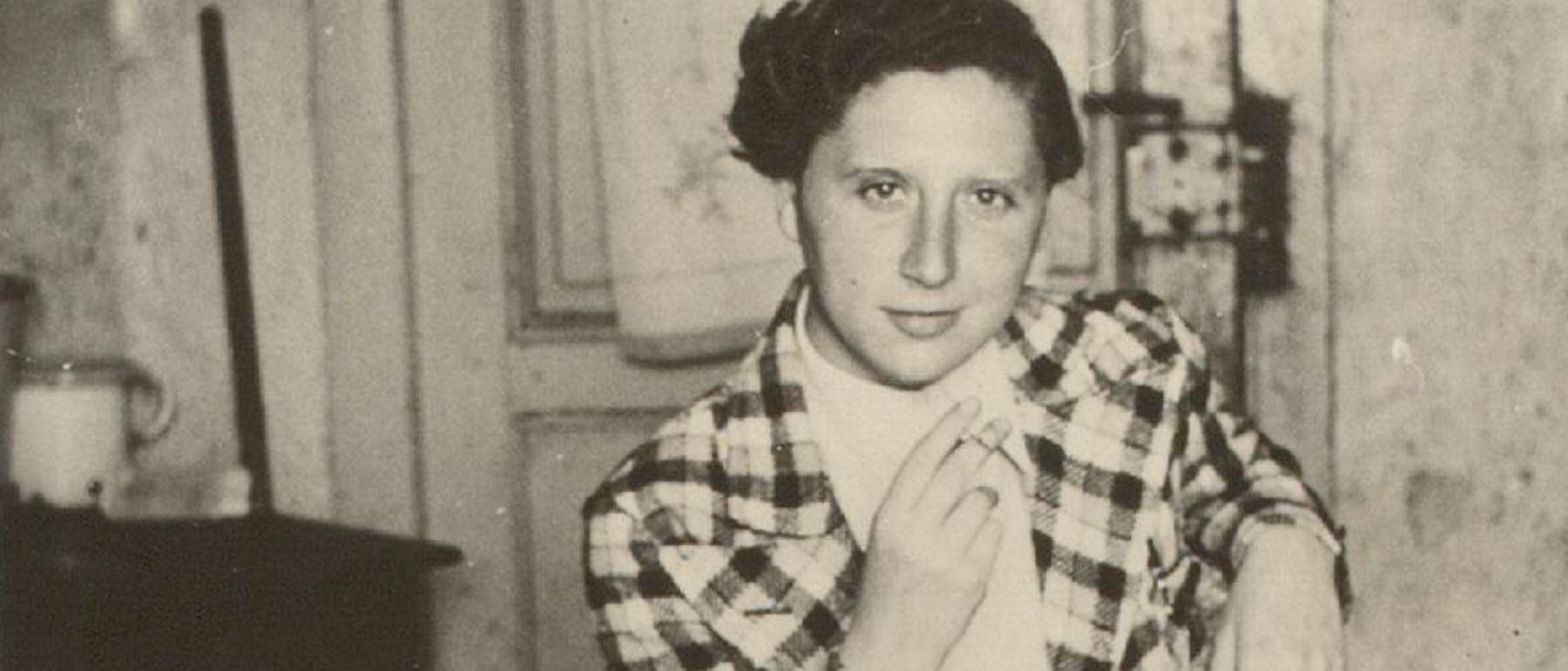 Une femme brune regarde l'objectif en souriant, une cigarette à la main