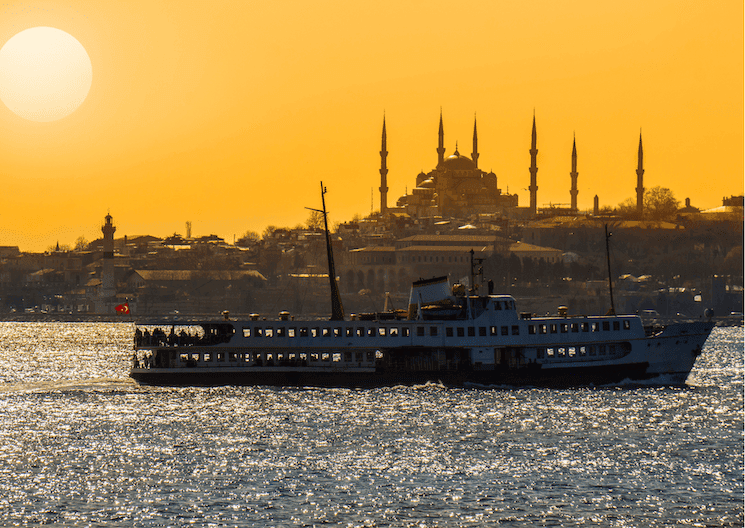 Ferry traversant le Bosphore au coucher du soleil, avec la Mosquée Bleue en arrière-plan à Istanbul en juin.