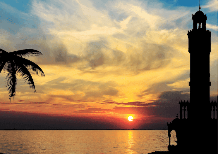 Coucher de soleil sur la baie d’Izmir avec la silhouette de la tour de l’horloge et un palmier